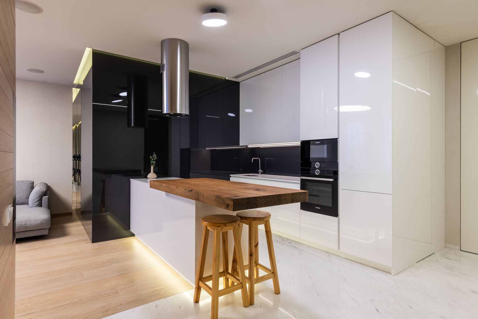 Intérieur d'un appartement moderne avec un coin cuisine meublé d'armoires brillantes et un coin salon avec canapé