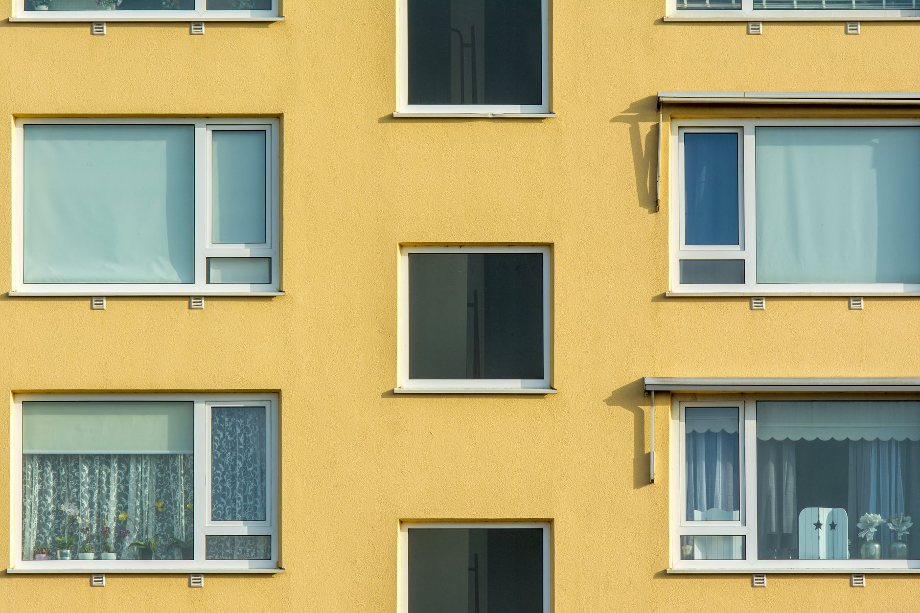 Gros plan sur la façade d'un immeuble d'appartements jaune avec des fenêtres et des balcons.